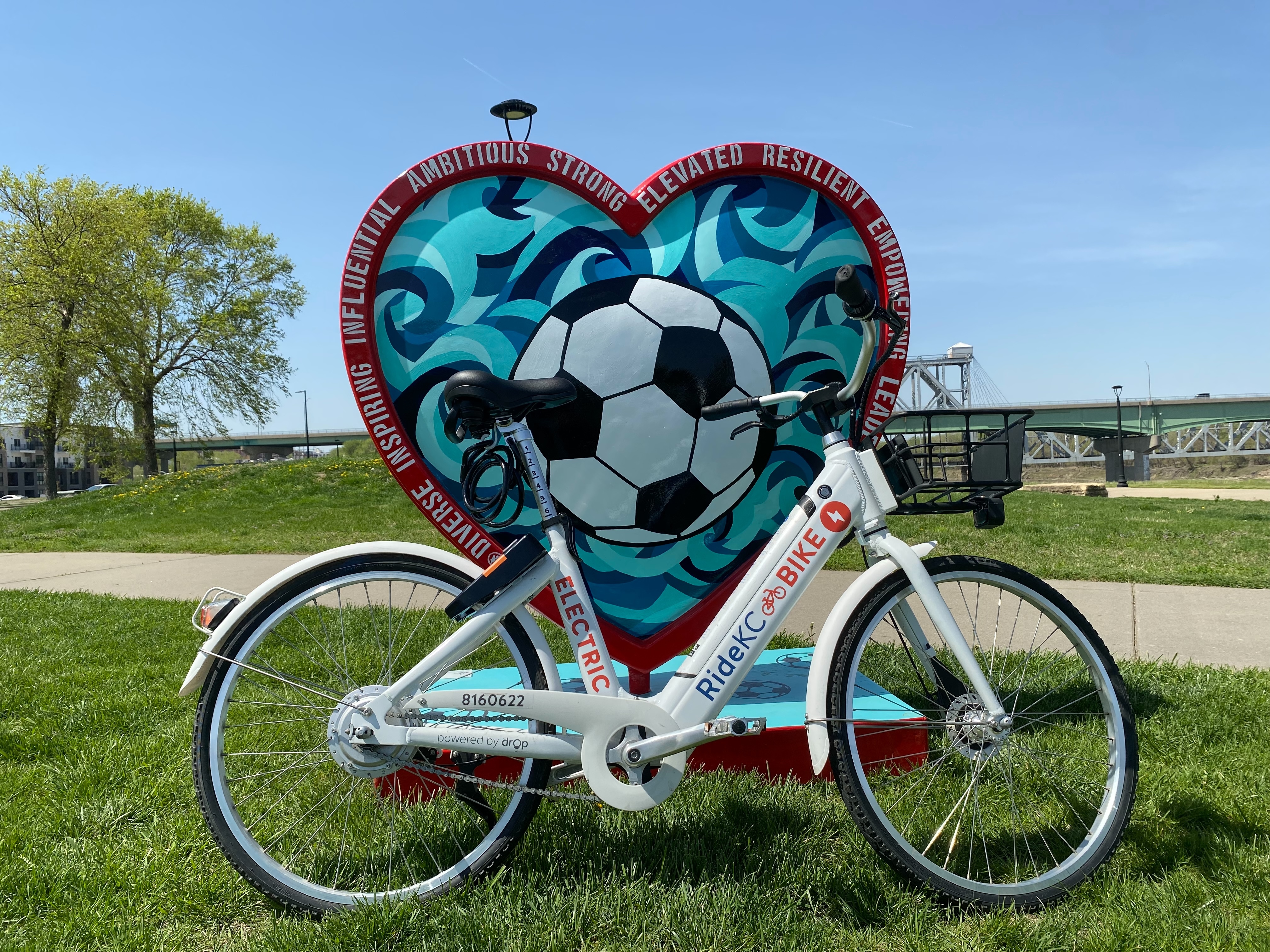 A Bike Share KC bike parked in front of a KC Heart celebrating soccer in Kansas City